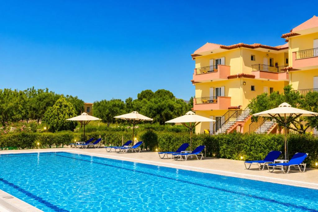 a swimming pool with chairs and umbrellas next to a building at Nautilos Hotel in Soullároi
