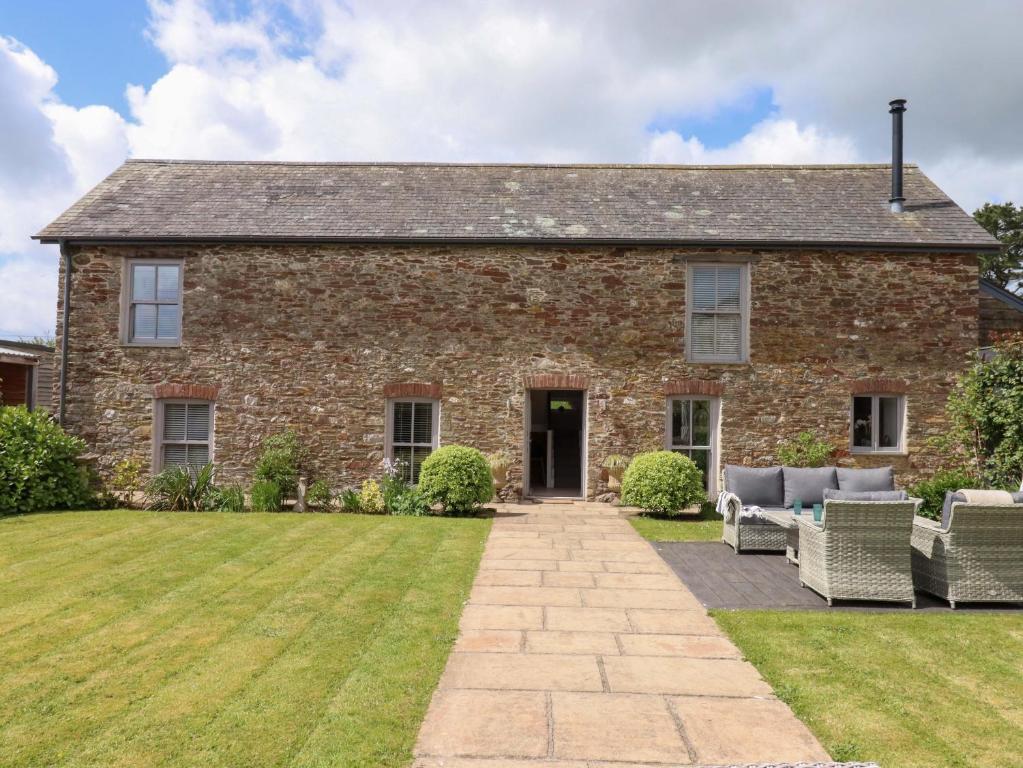 an old stone house with chairs and a lawn at Duke's Barn in Totnes