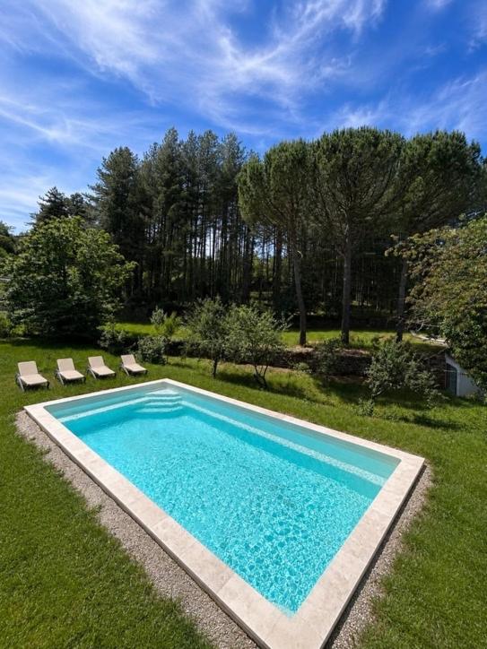 a swimming pool in a yard with two lawn chairs at Villa les pins in Chambonas