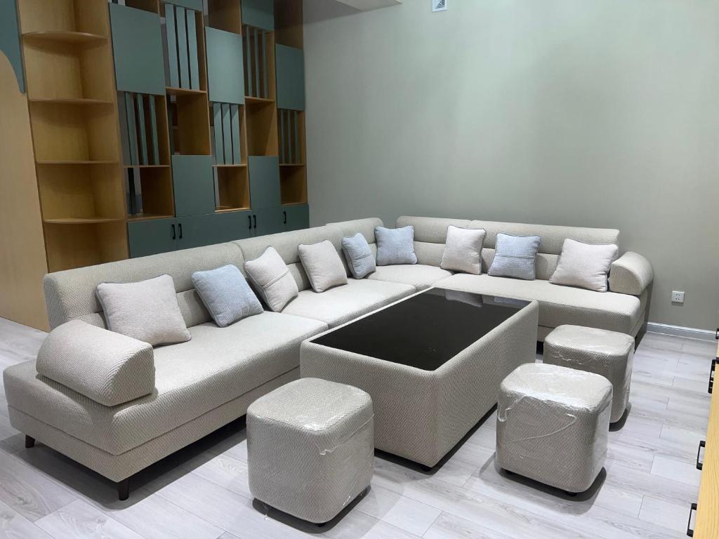 a living room with a large white couch and stools at Beshik Apartment 2 in Samarkand