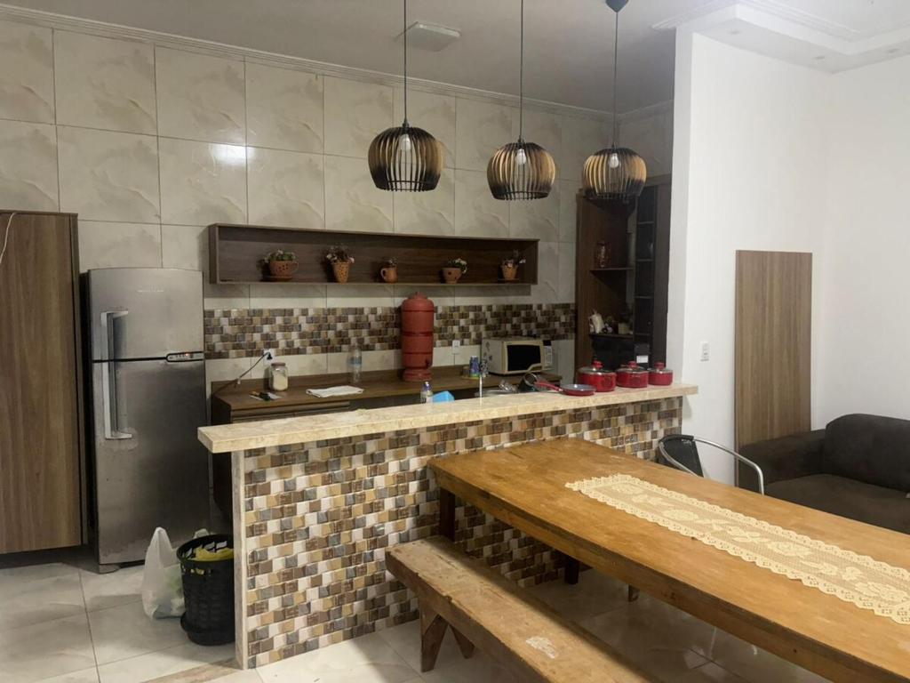 a kitchen with a table and a refrigerator at Casa espaçosa em Itacimirim com piscina e churrasqueira! in Camaçari