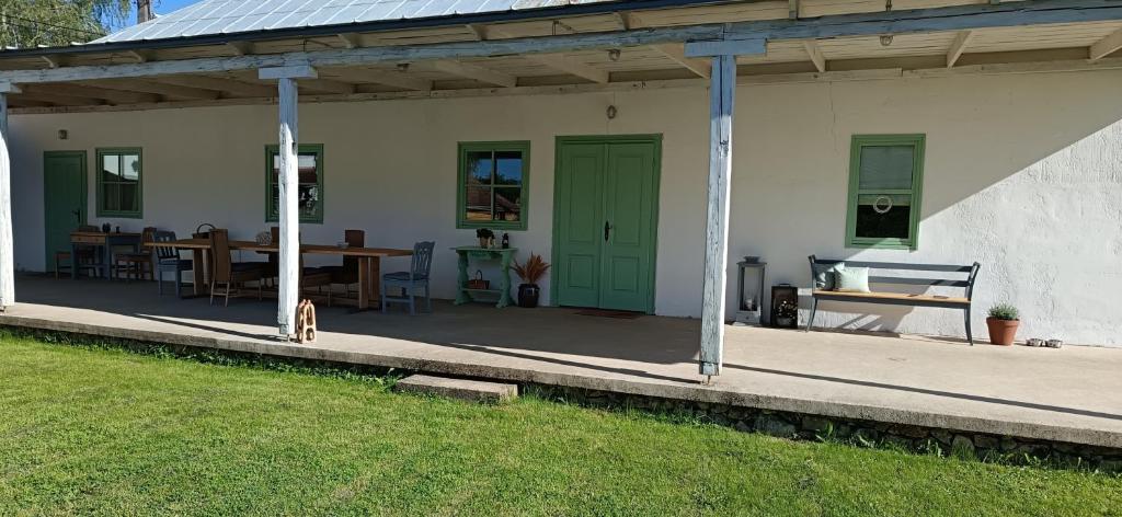 a patio with a table and green doors on a house at Tornác Vendégház in Diszel