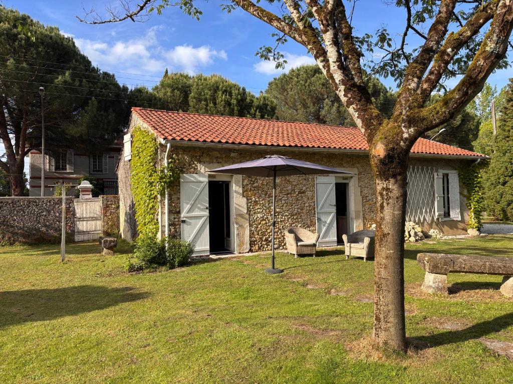 a small house with an umbrella in a yard at Gîte Landes d armagnac in Roquefort