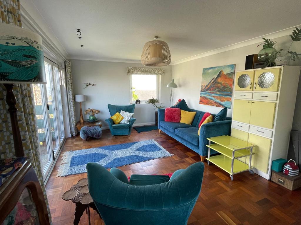 a living room with a blue couch and chairs at Mid-Century Gem Steps from the Beach in Edinburgh