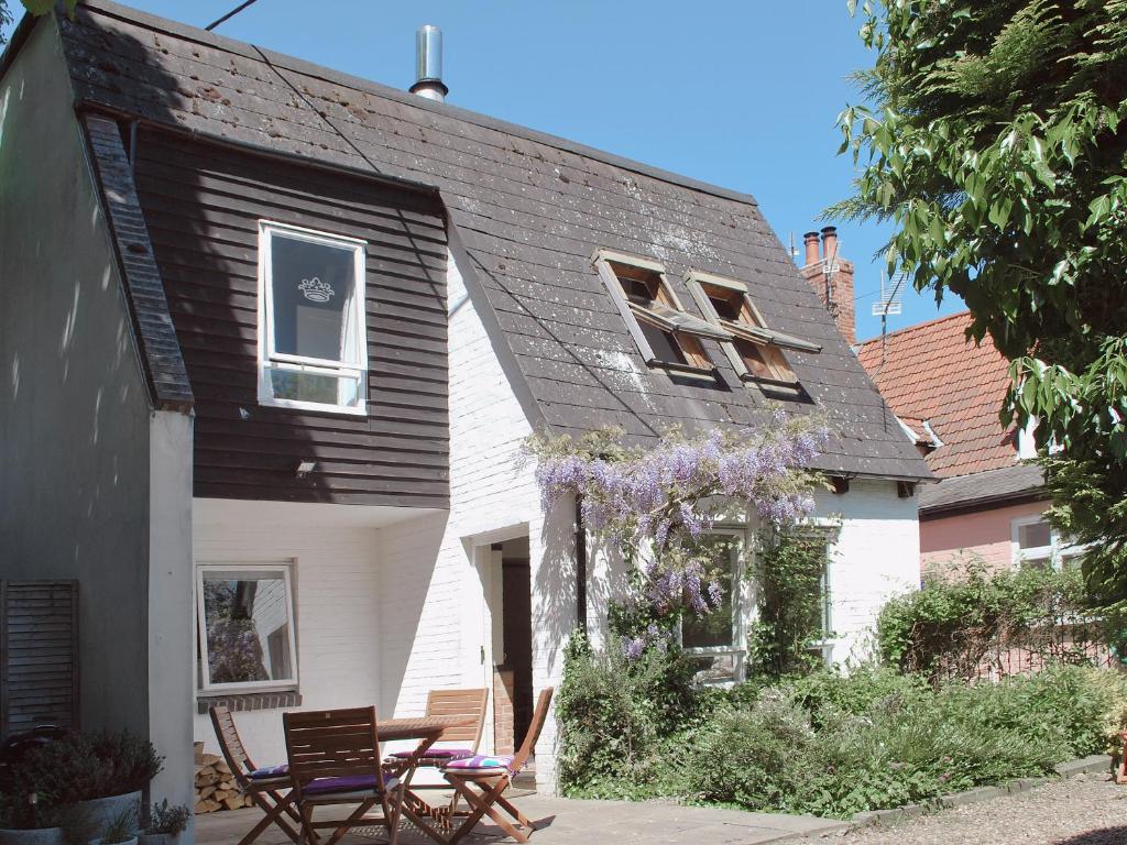a white house with a black roof and two chairs at Crown Cottage in Hartest