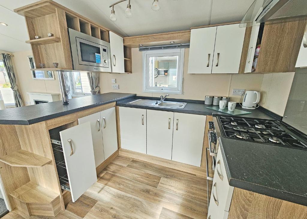 a kitchen with white cabinets and black counter tops at Aldbrough Leisure Park in Aldbrough