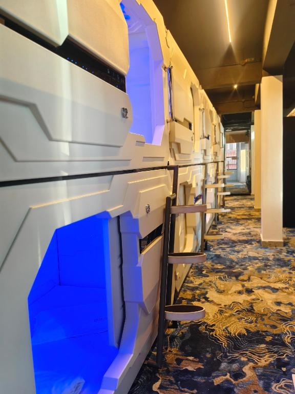 a hallway with blue and white walls and a chair at TRIVPODS Capsule Hotel in Trivandrum