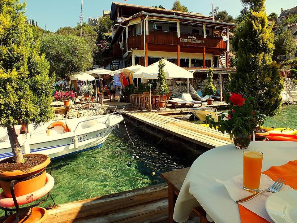 un restaurante con barcos en el agua junto a un edificio en Sahil Pension en Kaleucagız
