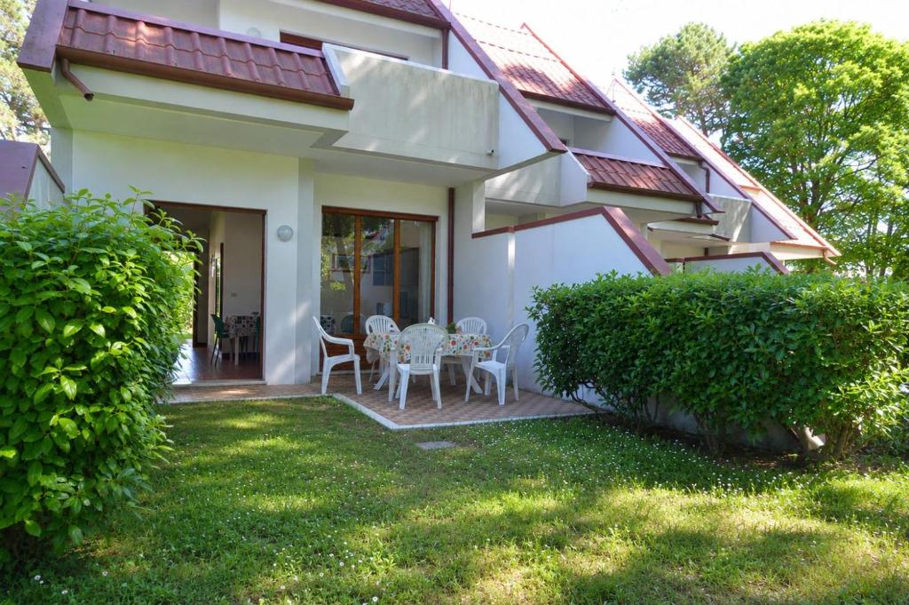 a house with a patio with tables and chairs at Villaggio Marina in Bibione