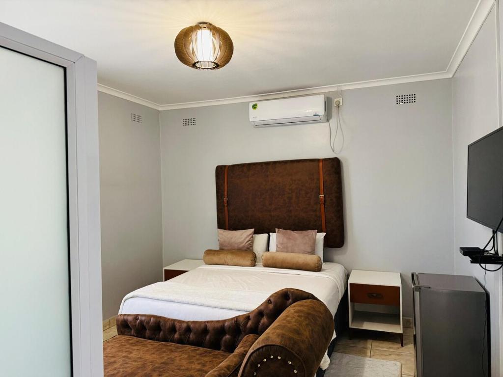 a bedroom with a bed and a couch at Kim Guesthouse in Harare