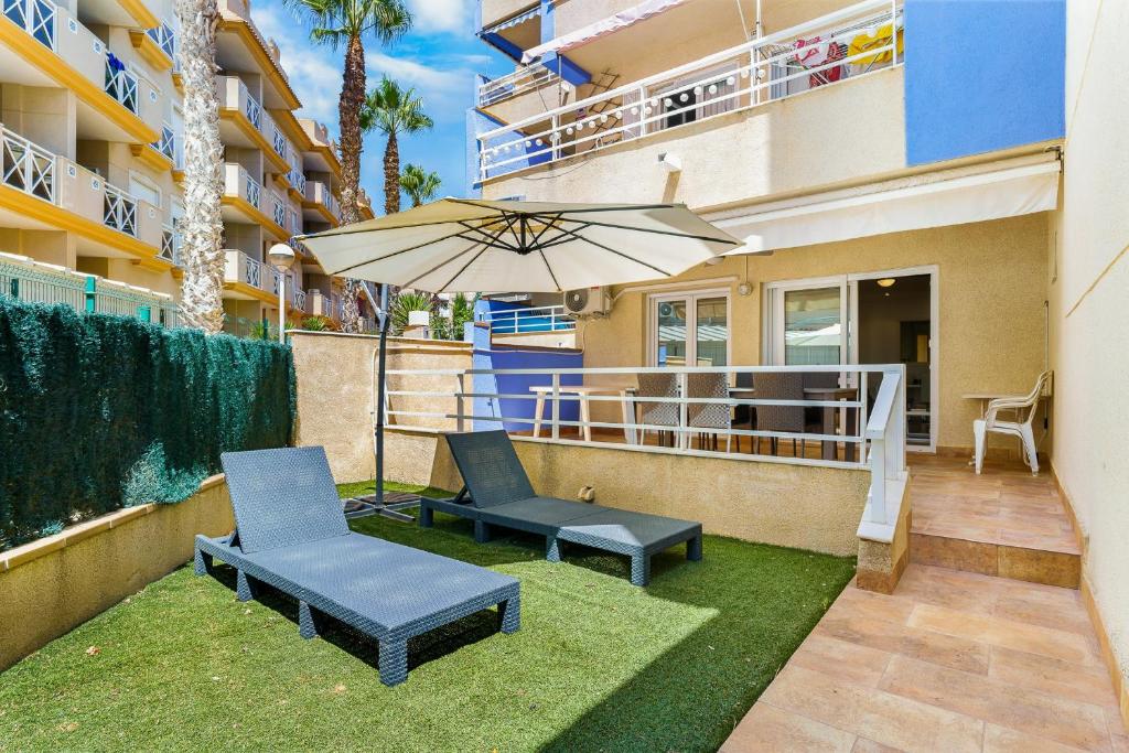 a patio with two chairs and an umbrella at Aguamarina 2 Sunrise in Orihuela