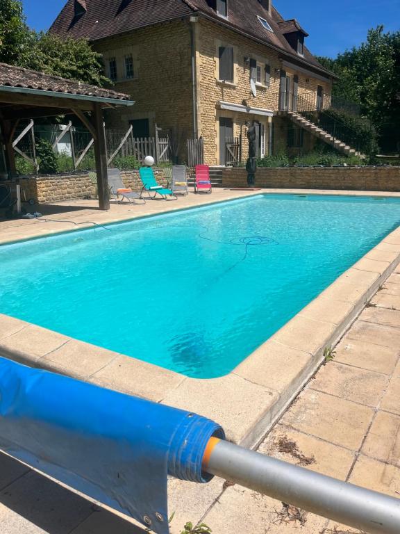 a large blue swimming pool in front of a house at Le Clos Périgourdin in Église-Neuve-de-Vergt