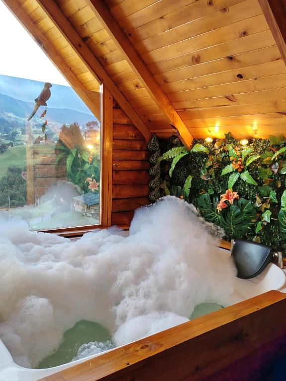 a bathtub filled with clouds in a room with a window at Glamping El Ocaso in Zipaquirá