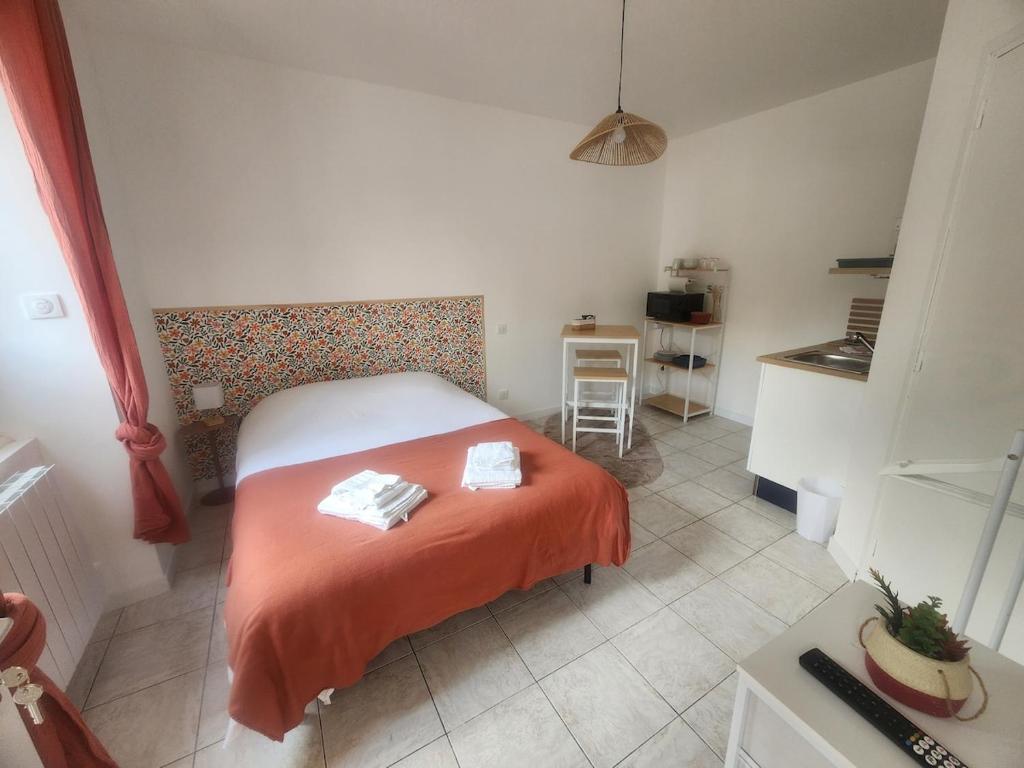 a bedroom with a bed with an orange blanket at Le Petit Lamballais in Lamballe Armor