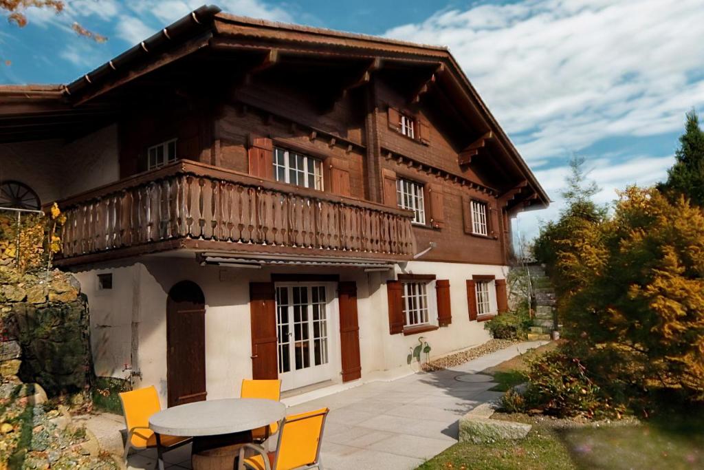 ein Haus mit einem Tisch und Stühlen davor in der Unterkunft Ferienhaus Tanzhaus - Sauna & Bergblick in Wildhaus