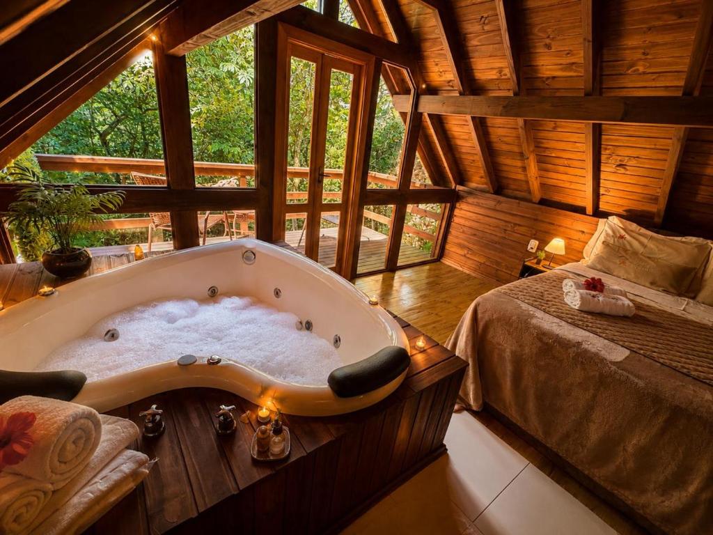 a large bath tub in a room with a bed at Cabanas dos Plátanos in Gramado