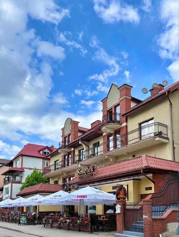 a hotel with tables and umbrellas in front of it at Apartamenty Smętek in Ełk