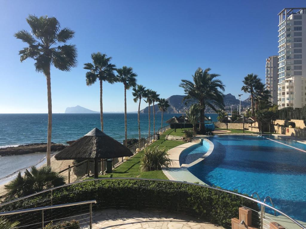 una piscina junto al océano con palmeras en Paradero Rental S74 - Vistas al Mar, en Calpe