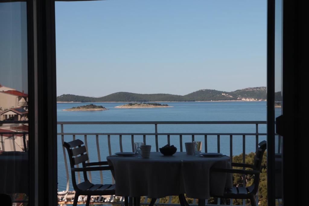 a table on a balcony with a view of the water at Apartman Mala Artica in Drage