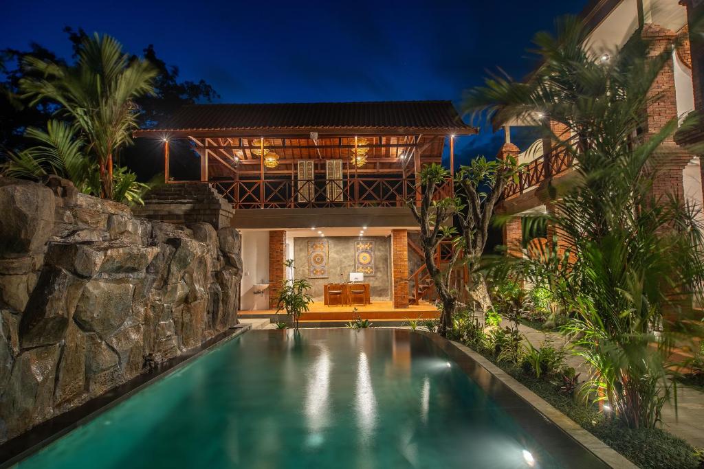 a swimming pool in front of a house at night at Soulstar Villa Ubud in Ubud