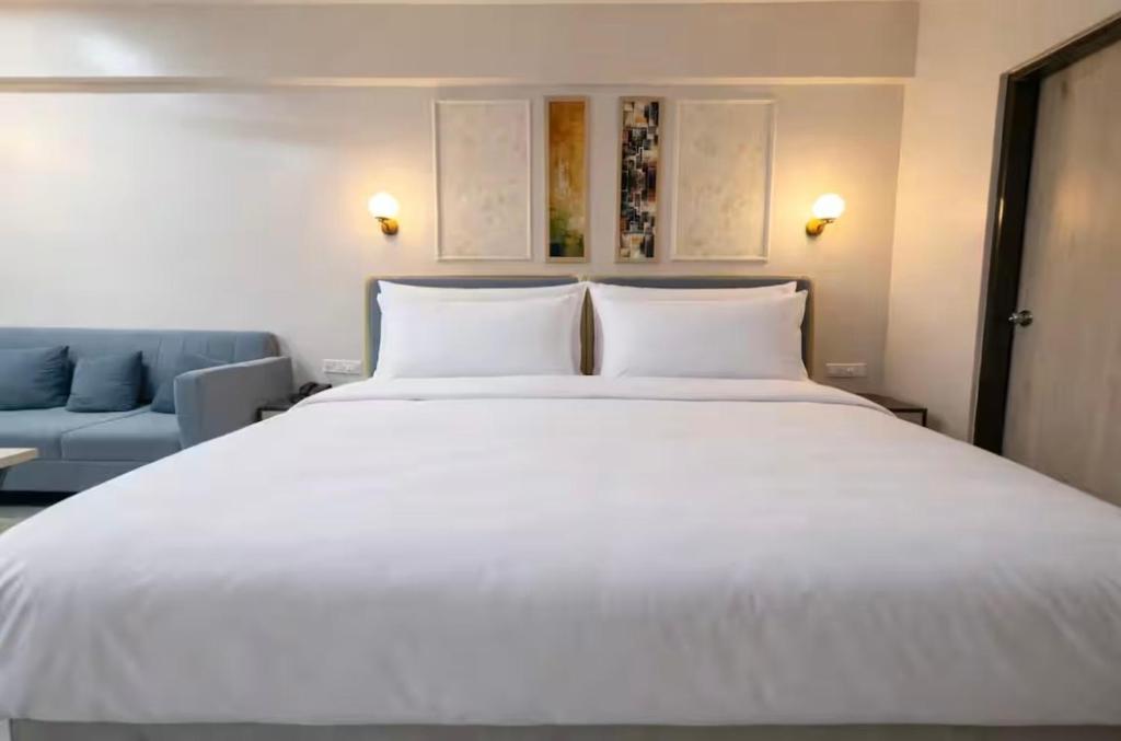 a bedroom with a large white bed and a blue couch at Belle Vue Stays in Jaipur
