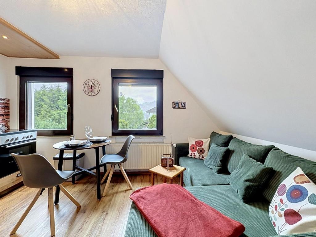 a living room with a green couch and a table at Apartment Eifelhome Two nahe Nürburgring by Interhome in Fuchshofen