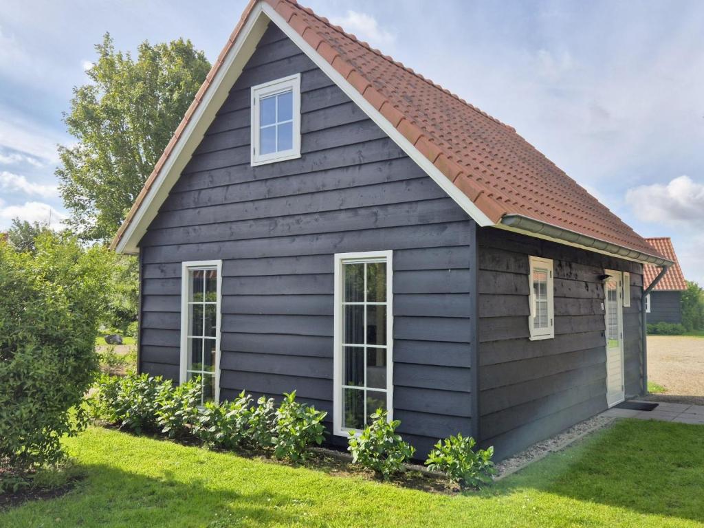 a black house with a red roof at Holiday Home Zeeuwse Cottage Wemeldinge-1 by Interhome in Wemeldinge