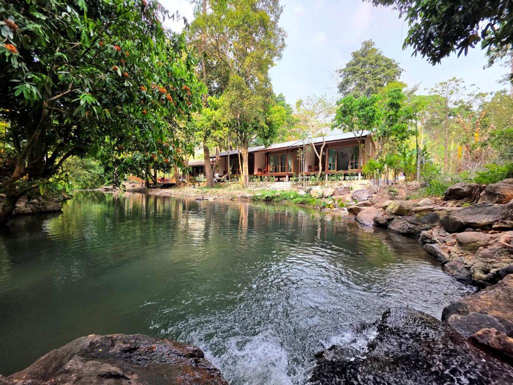 a river in front of a building with trees at ลิตเติ้ล แคมป์ ชะอม in Ban Bung Mai
