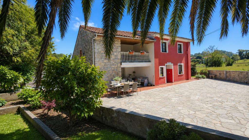 a villa with a red house with a patio at La Venta de Pedro in Ribadesella