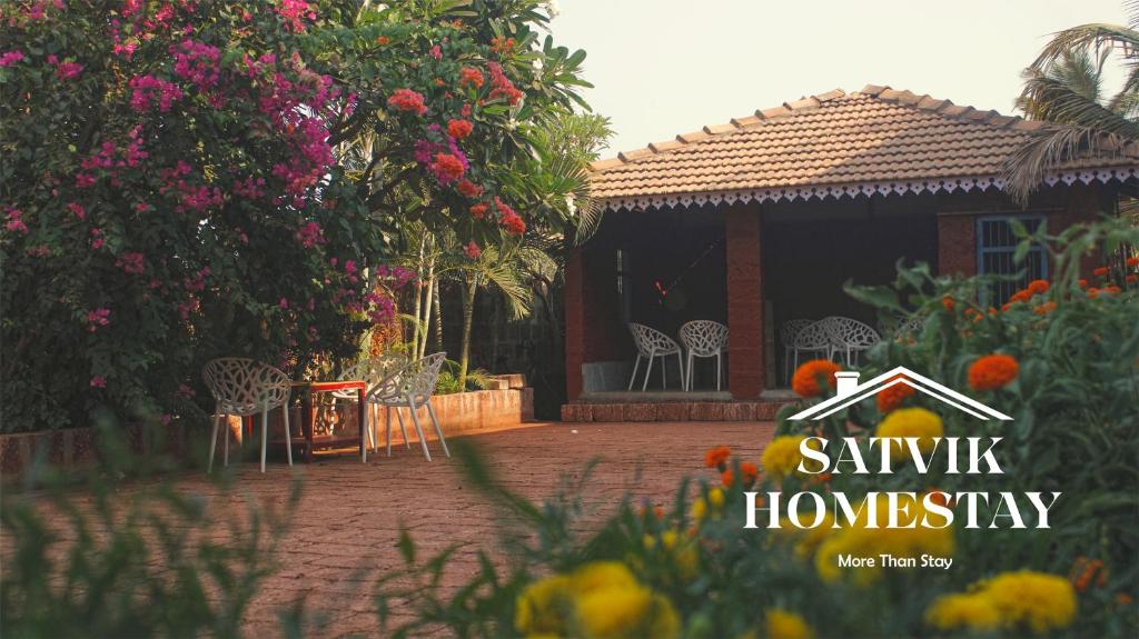 a house with chairs and flowers in front of it at Satvik Homestay in Devgarh