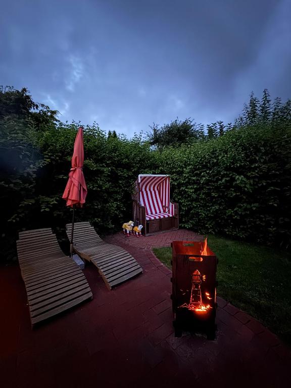a fire pit with a chair and an umbrella at Ferienhaus Menkhoff in Dornumersiel