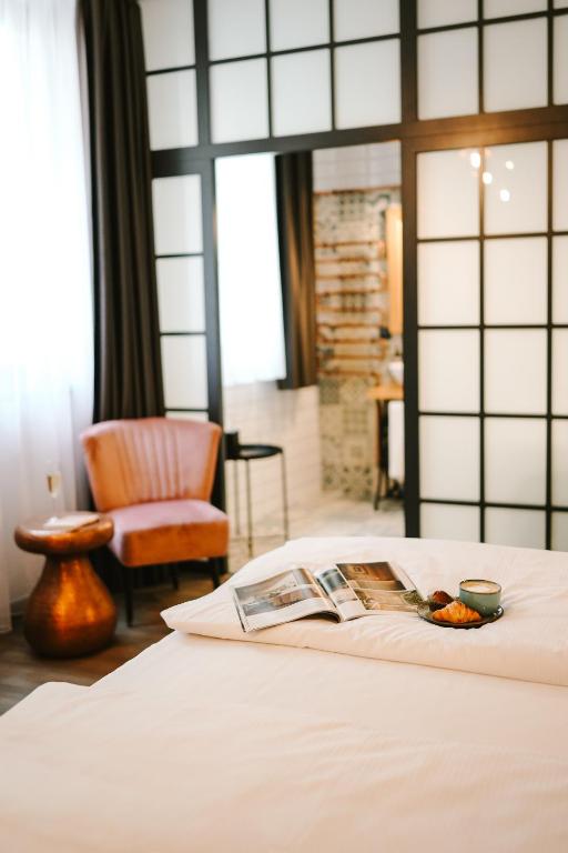 a bed with a magazine on it with a chair at Hotel Memories OldTown in Budapest