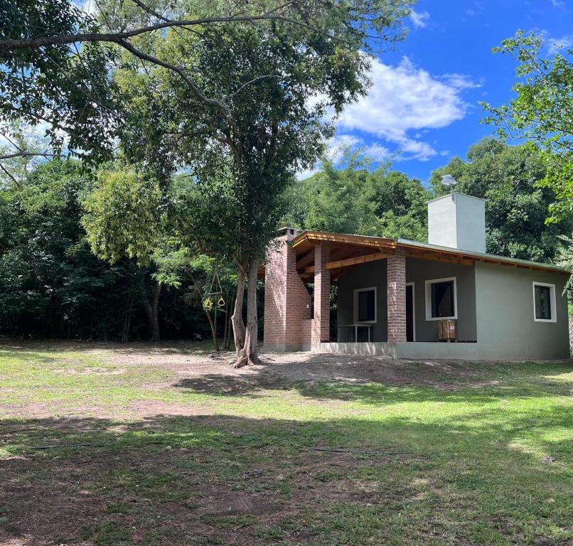 a small house with a tree in front of it at Cabañas Nido Escondido in Villa Ciudad Parque