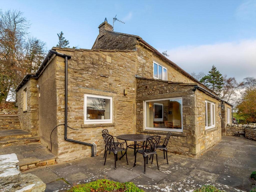 a stone house with a table and chairs in front of it at Griff Head Cottage in Carlton