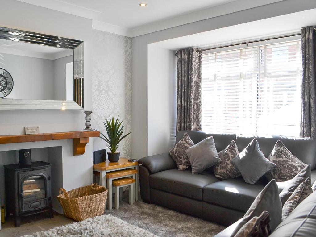 a living room with a black leather couch and a fireplace at Lowey's Harbour Cottage in Bridlington