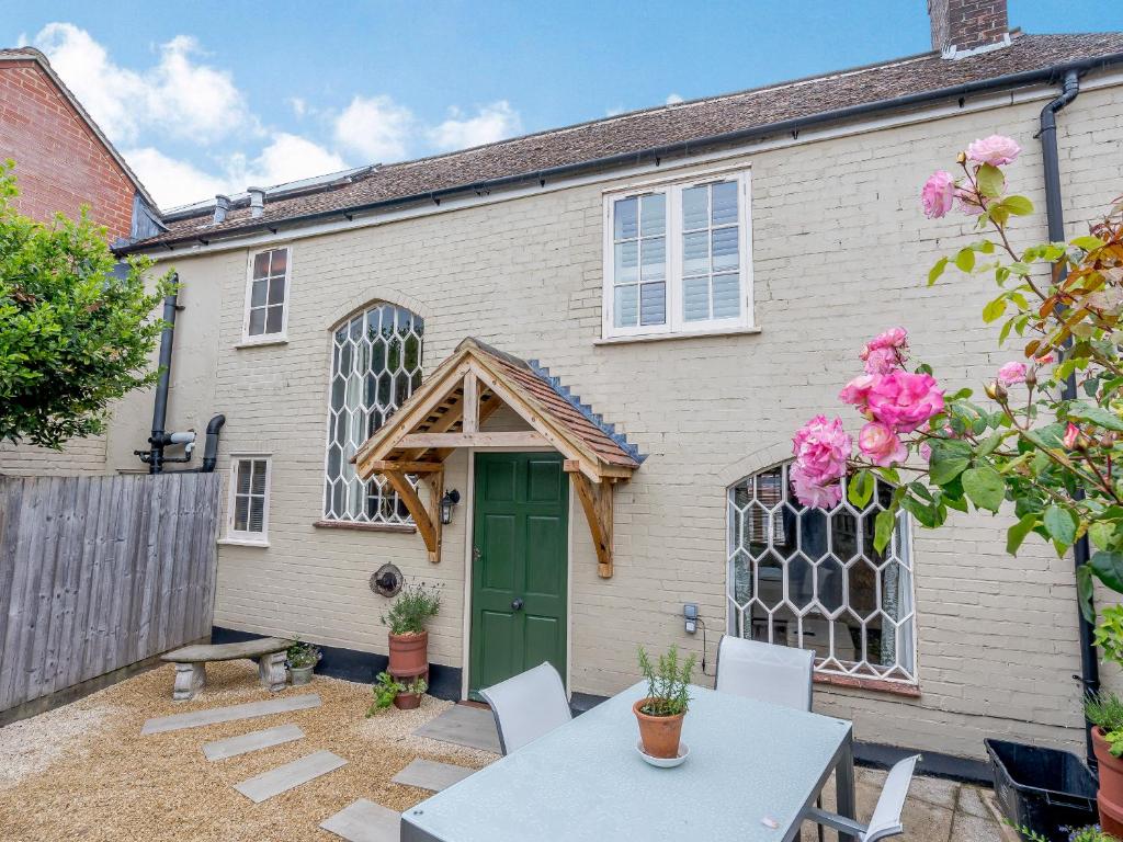 a house with a green door and a table and chairs at Duck Island Cottage in Ringwood