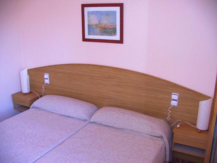 a bedroom with a bed with a wooden head board at Masllandrich Hostal Rural in Porqueres