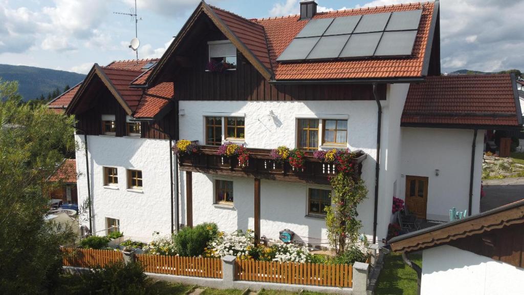 a white house with a balcony with flowers on it at Ferienwohnung Christina in Mauth