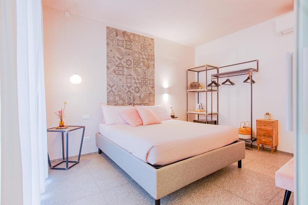 a bedroom with a bed with white sheets and pink pillows at B&B Fontanella 32 in Porto SantʼElpidio