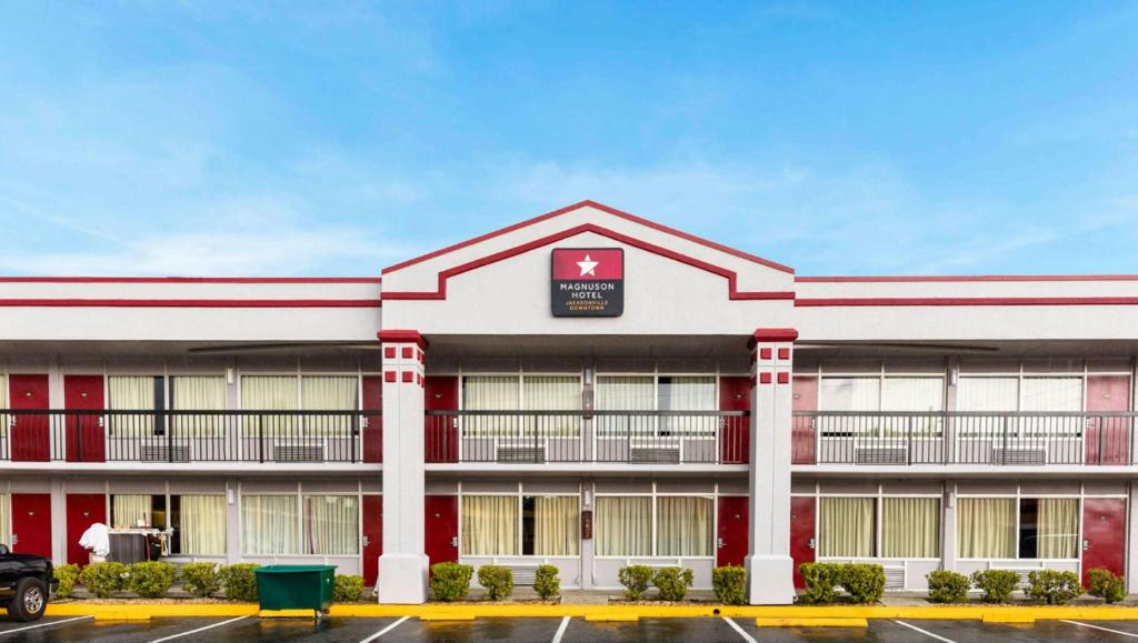 a large red and white building with a parking lot at Magnuson Hotel Jacksonville Downtown in Jacksonville