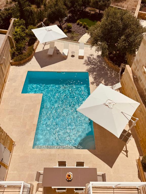 an overhead view of a swimming pool with umbrellas at Villa La Mola Gozo Luxury Villa with Private Pool & Sunset Views in Għasri
