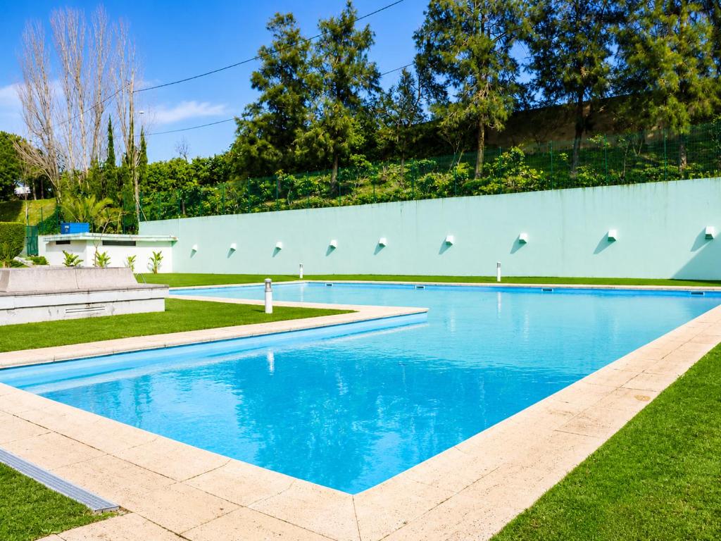 a swimming pool with blue water in a yard at Lisbon Lux T1 Pool Gym Tennis AC - Pouso dos Anjos Apartment in Lisbon