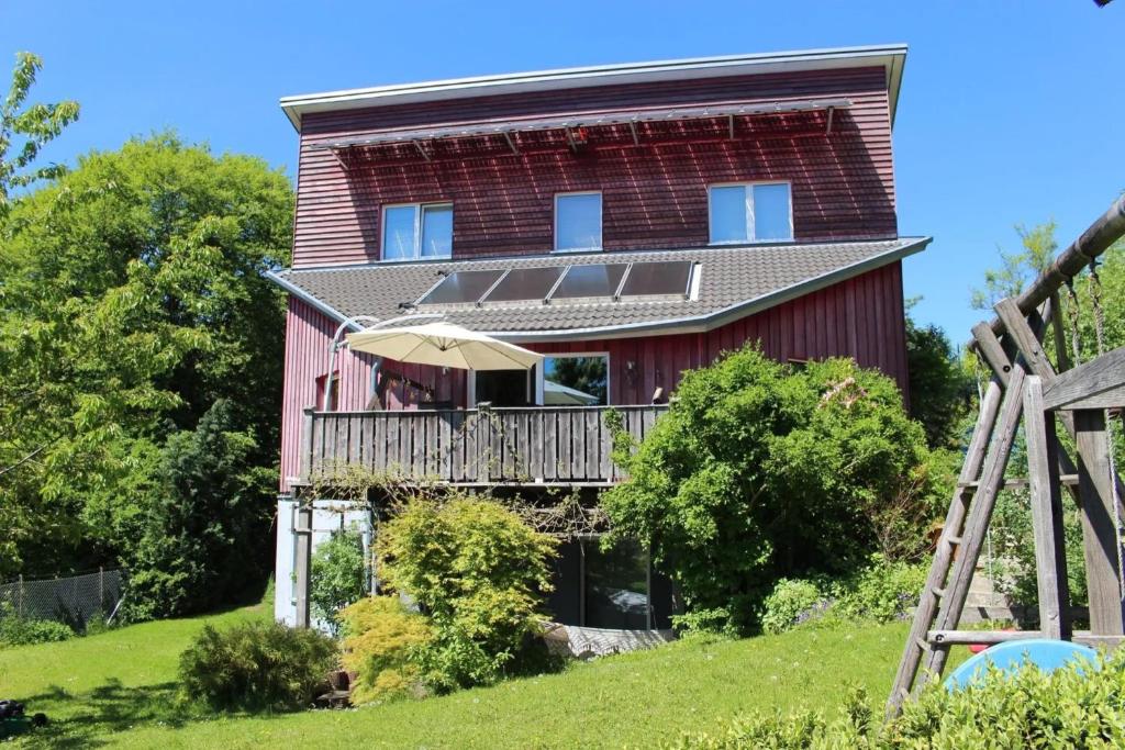 a red house with a balcony and an umbrella at Paula in Bitz