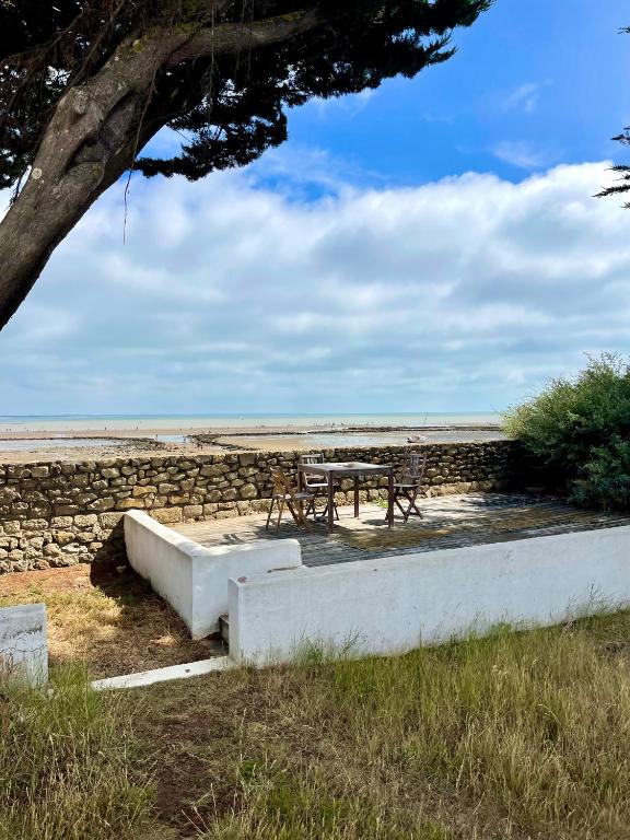 a picnic table and bench next to a stone wall at Charmante maison front de mer avec jardin in La Guérinière