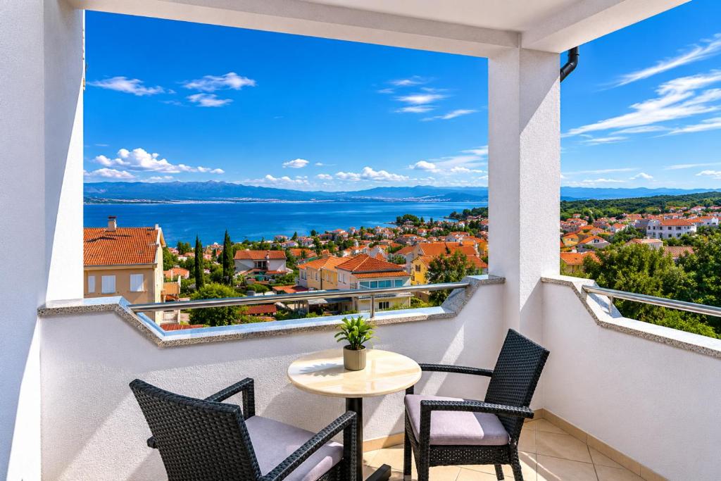 a balcony with a table and chairs and a view of the water at Apartments Kvarner in Malinska
