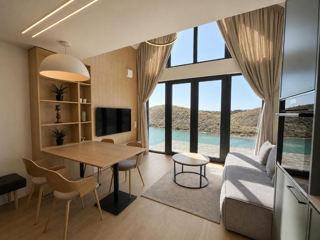 a living room with a table and a large window at Pirtelių resort - Mėlynasis namelis in Kiauleikiai