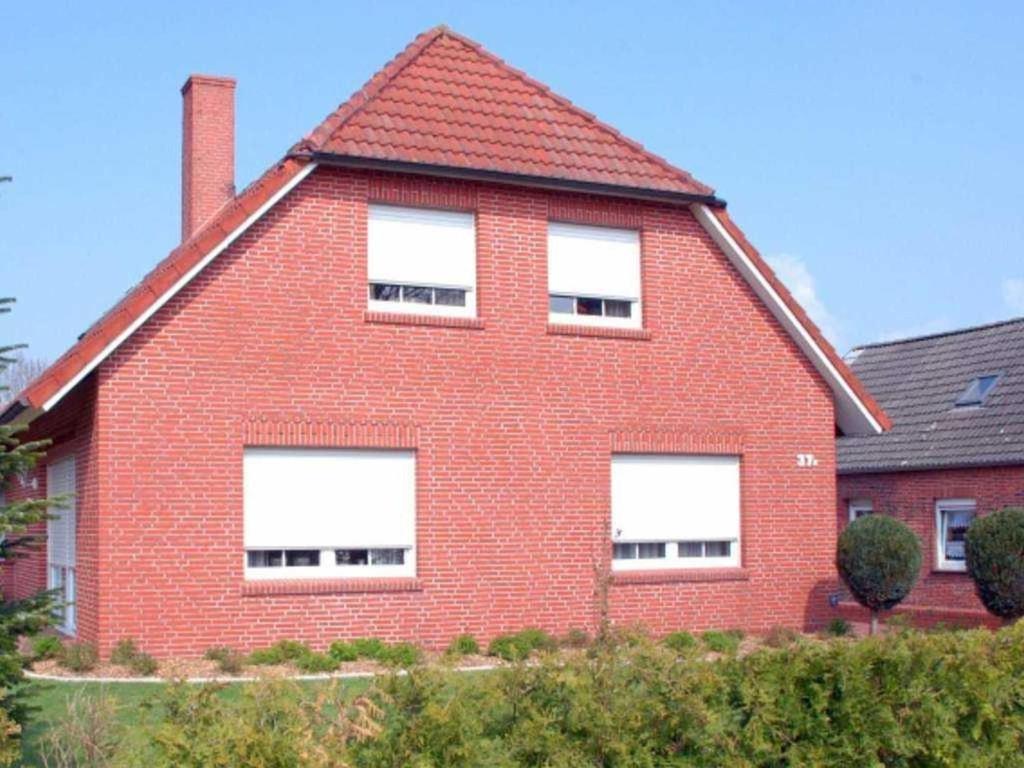 a large red brick house with white windows at Ferienwohnung Sonnenberg, 25502 in Weener