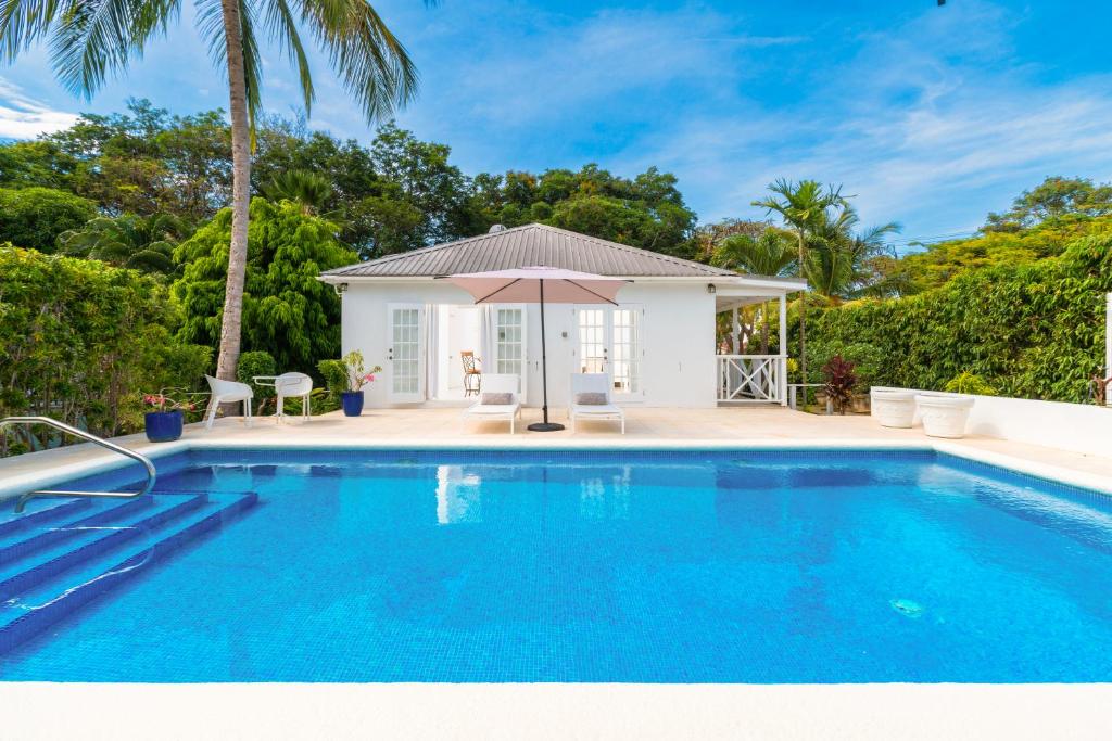 a swimming pool in front of a villa at Gibbs Cottages in Saint Peter