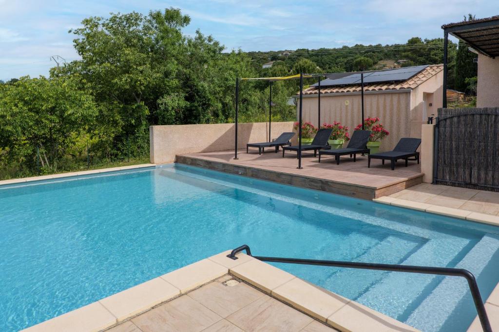 a large swimming pool with two chairs and a house at Résidence Château Saint Martin in Saint-Martin-dʼArdèche