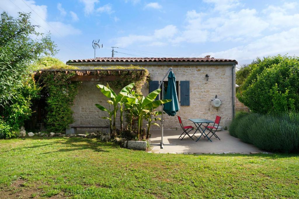 a patio with a table and an umbrella in front of a house at Gîte de la Barrière in Sainte-Gemme
